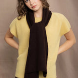 a woman wears a cashmere tee in butter yellow over silk trousers in chocolate brown with a cashmere scarf in chocolate brown on top