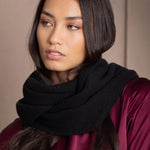 A woman wears a black cashmere infinity scarf snood by Irish brand Madigan Cashmere