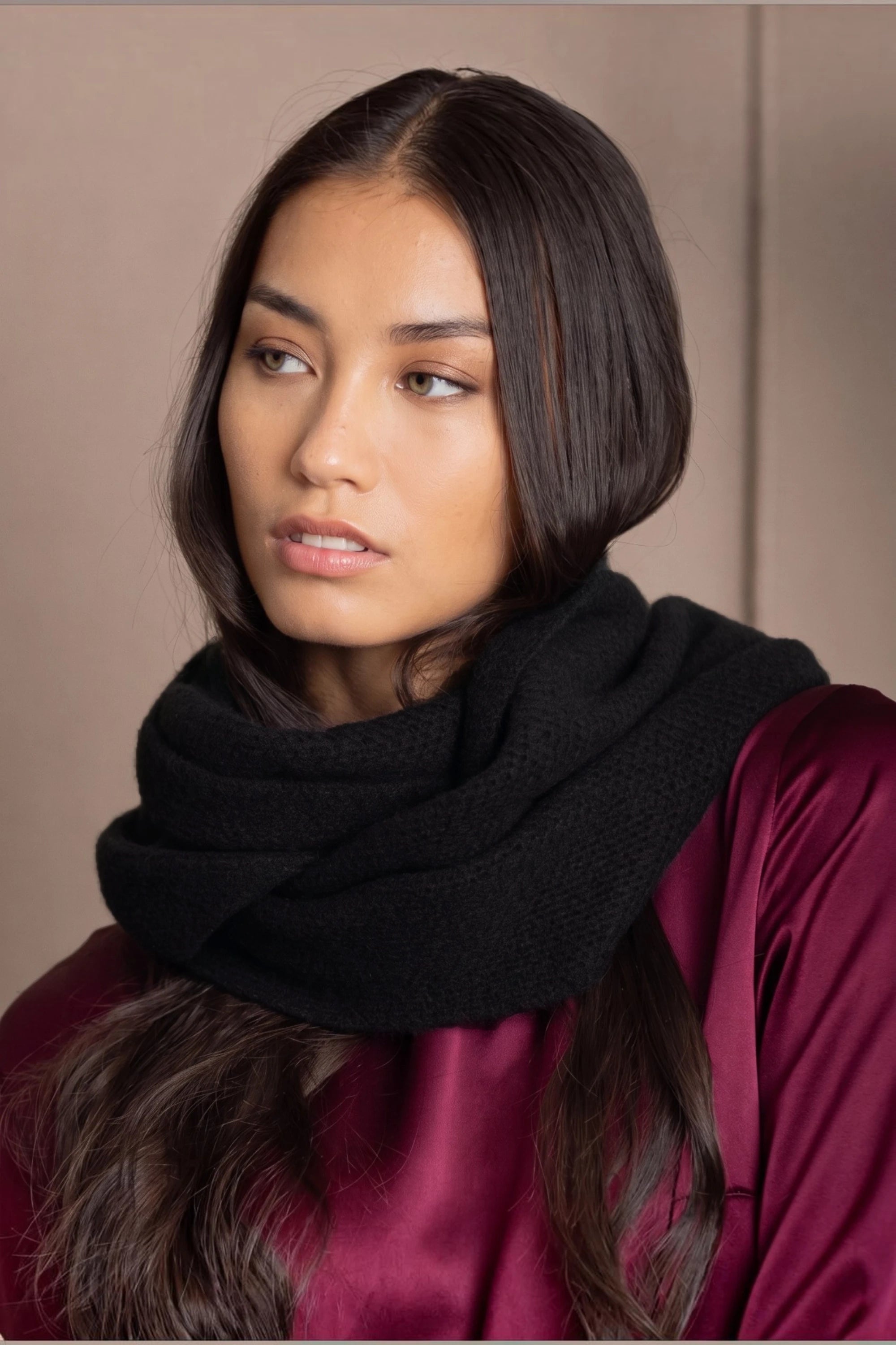 A woman wears a black cashmere infinity scarf snood by Irish brand Madigan Cashmere