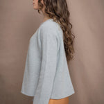 a woman wearing a light blue pure cashmere raglan sleeve sweater jumper over silk skirt in bronze