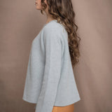 a woman wearing a light blue pure cashmere raglan sleeve sweater jumper over silk skirt in bronze