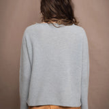 a woman wearing a light blue pure cashmere raglan sleeve sweater jumper over silk skirt in bronze
