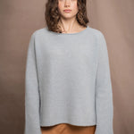a woman wearing a light blue pure cashmere raglan sleeve sweater jumper over silk skirt in bronze