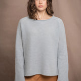 a woman wearing a light blue pure cashmere raglan sleeve sweater jumper over silk skirt in bronze
