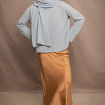 a woman wearing a light blue pure cashmere raglan sleeve sweater jumper and matching cashmere scarf over silk skirt in bronze