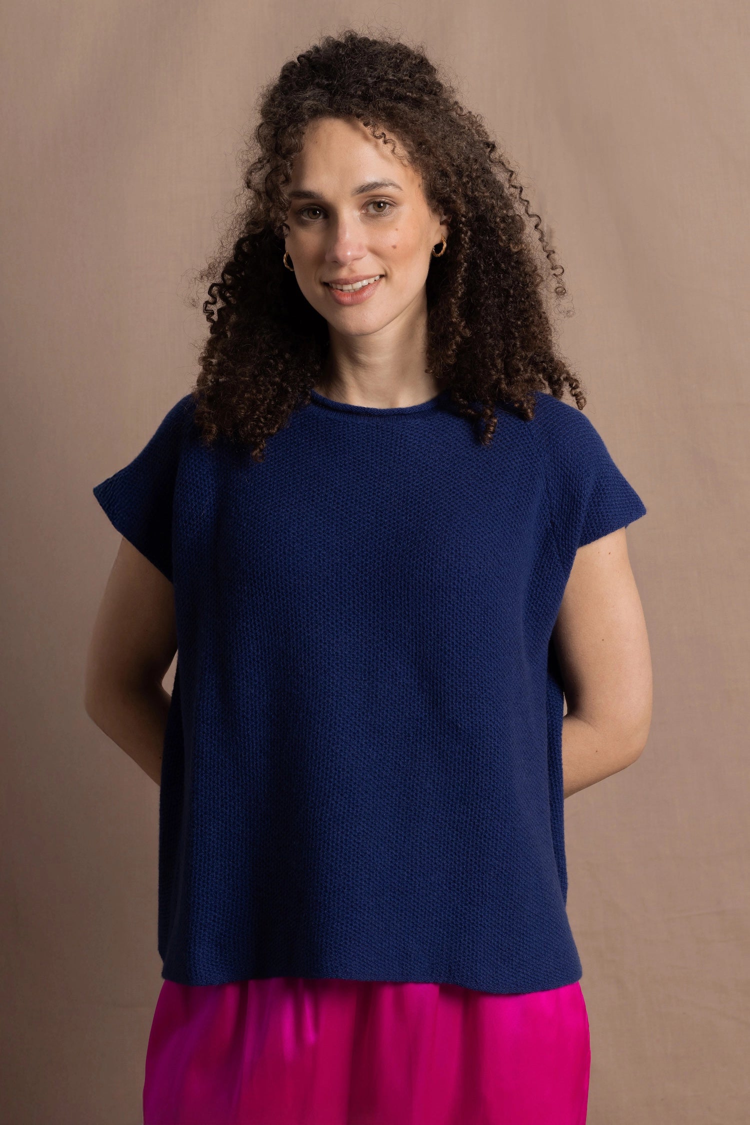 A lady wears a pure 100% cashmere tee sweater jumper in blue over bright pink silk trousers