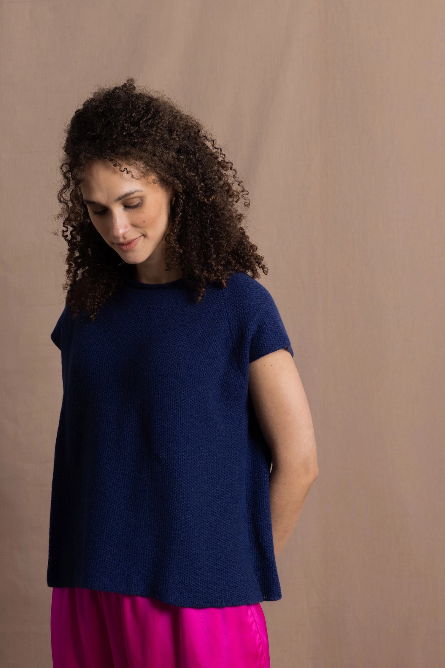 A lady wears a pure 100% cashmere tee sweater jumper in blue over bright pink silk trousers