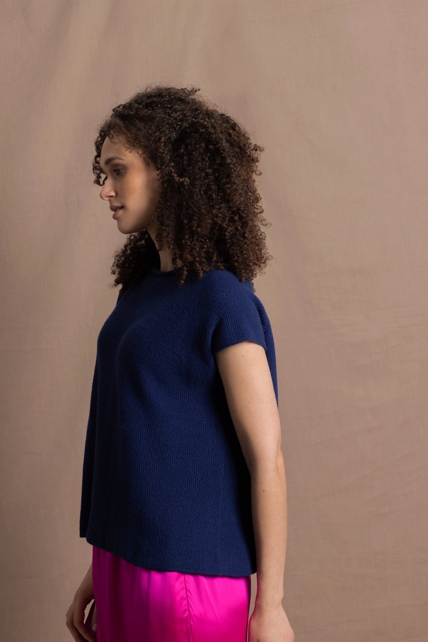A lady wears a pure 100% cashmere tee sweater jumper in blue over bright pink silk trousers