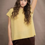 a woman wears a cashmere tee in butter yellow over silk trousers in chocolate brown 