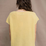 a woman wears a cashmere tee in butter yellow over silk trousers in chocolate brown 