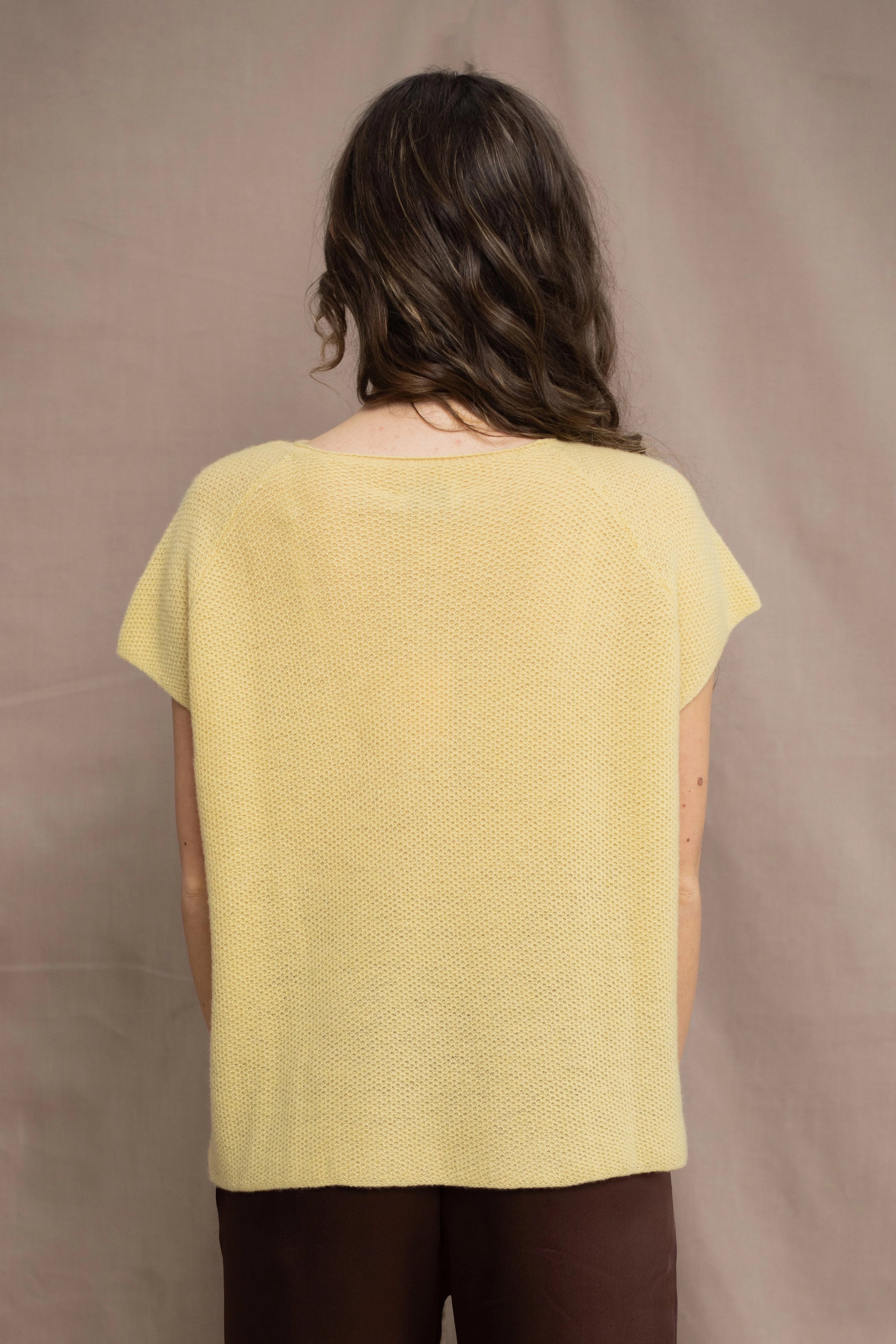 a woman wears a cashmere tee in butter yellow over silk trousers in chocolate brown 