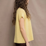 a woman wears a cashmere tee in butter yellow over silk trousers in chocolate brown 