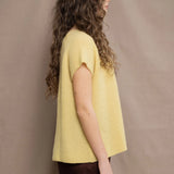 a woman wears a cashmere tee in butter yellow over silk trousers in chocolate brown 