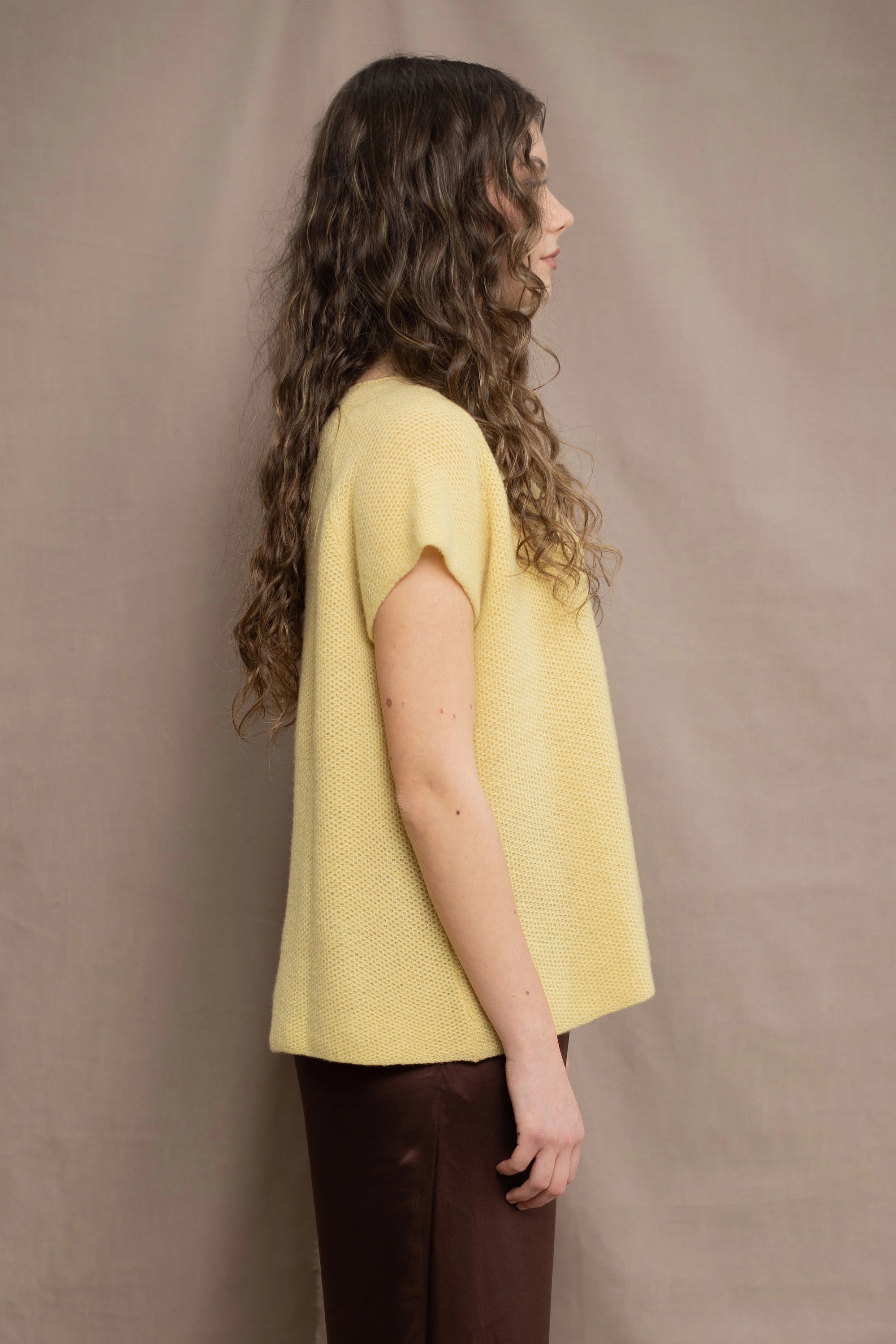 a woman wears a cashmere tee in butter yellow over silk trousers in chocolate brown 