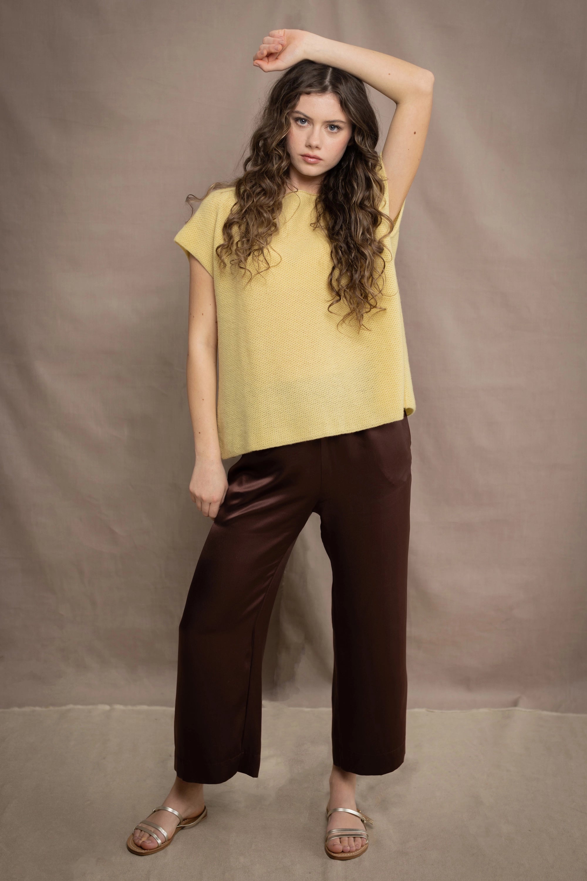 a woman wears a cashmere tee in butter yellow over silk trousers in chocolate brown 