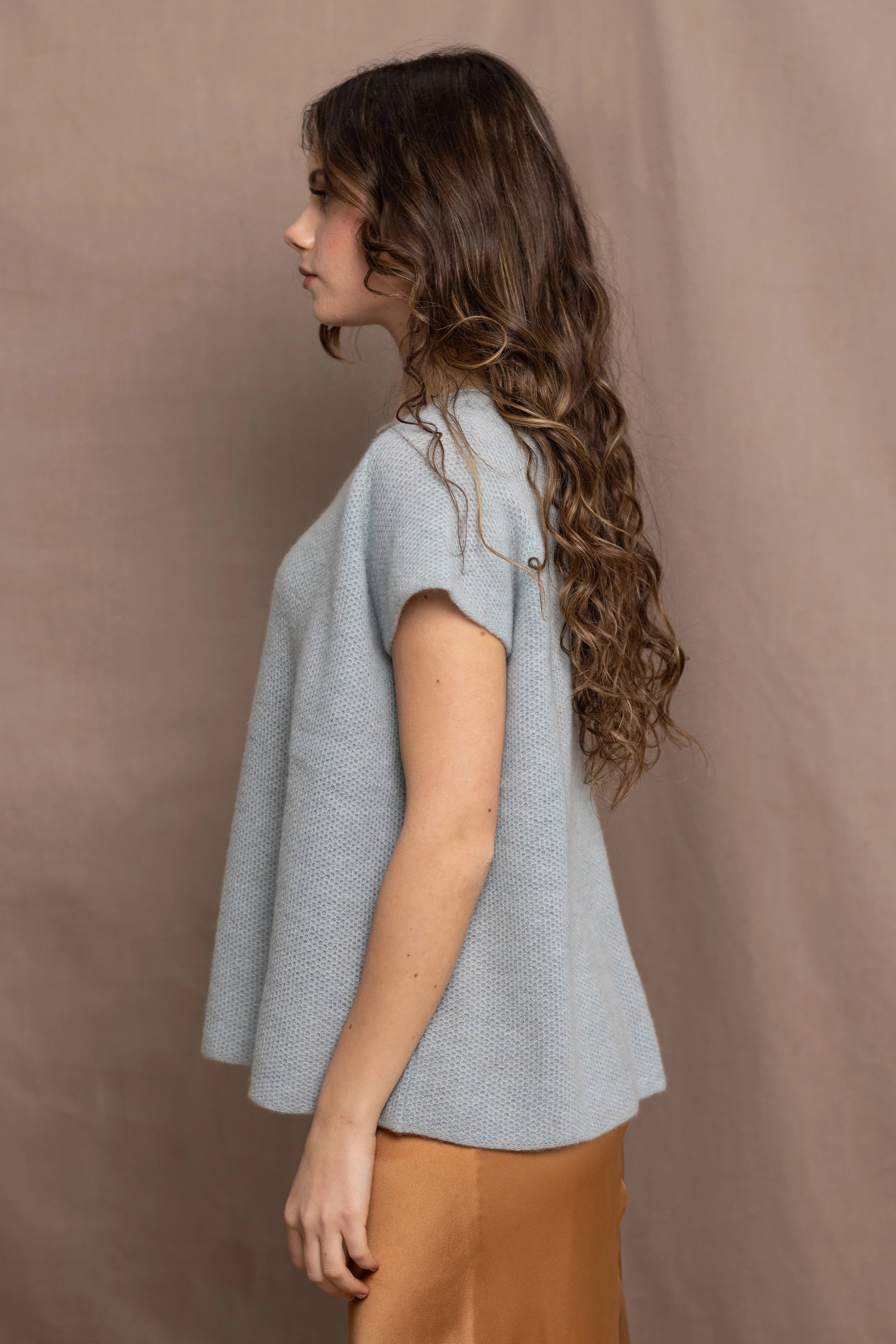 a woman wears a pure 100% cashmere tee sweater in pale light blue turquoise over a bronze silk skirt 