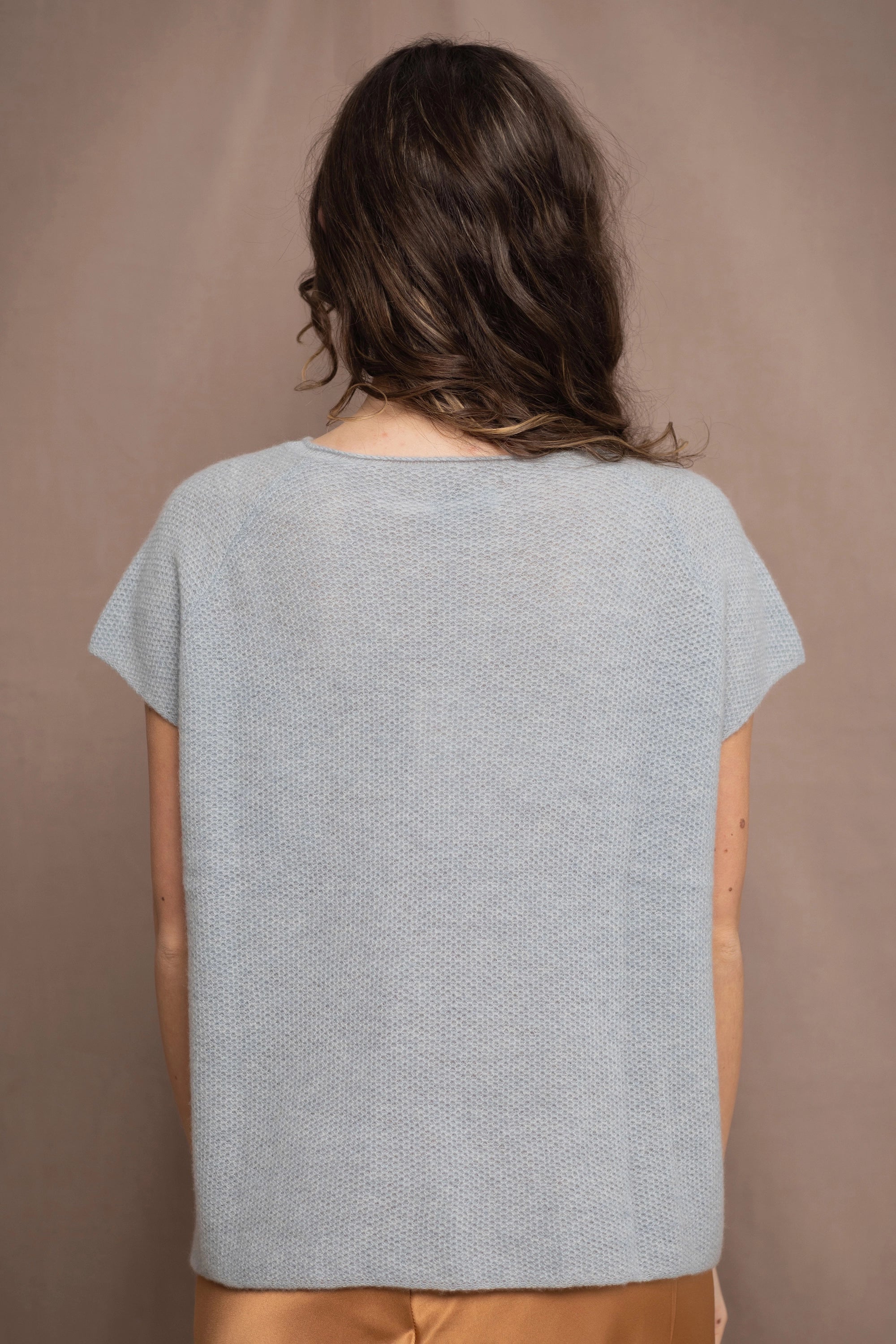 a woman wears a pure 100% cashmere tee sweater in pale light blue turquoise over a bronze silk skirt 