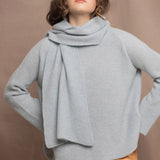 Woman wearing a pale blue cashmere scarf and sweater with a bronze silk skirt