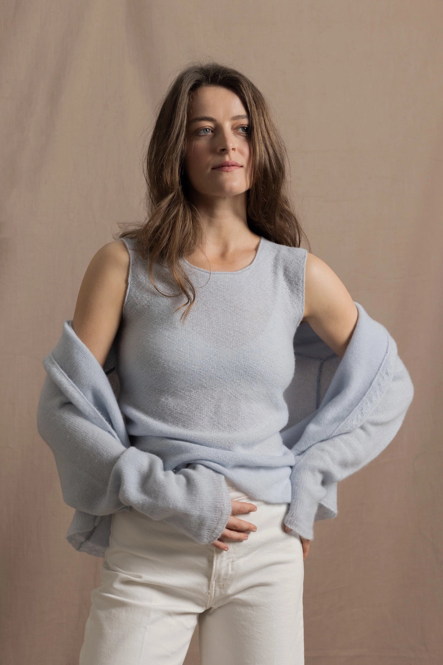 A woman wears a pure cashmere tee in pointelle texture in pale blue with cashmere cardigan on top in matching pale blue