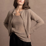 A woman wears a pure cashmere twinset cardigan with matching vest top in Beige with silk shorts in black