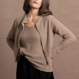 A woman wears a pure cashmere twinset cardigan with matching vest top in Beige with silk shorts in black