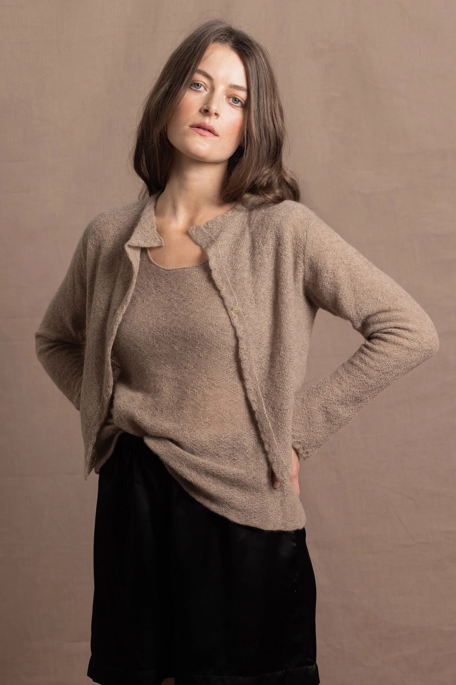 A woman wears a pure cashmere twinset cardigan with matching vest top in Beige with silk shorts in black