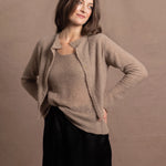 A woman wears a pure cashmere twinset cardigan with matching vest top in Beige with silk shorts in black