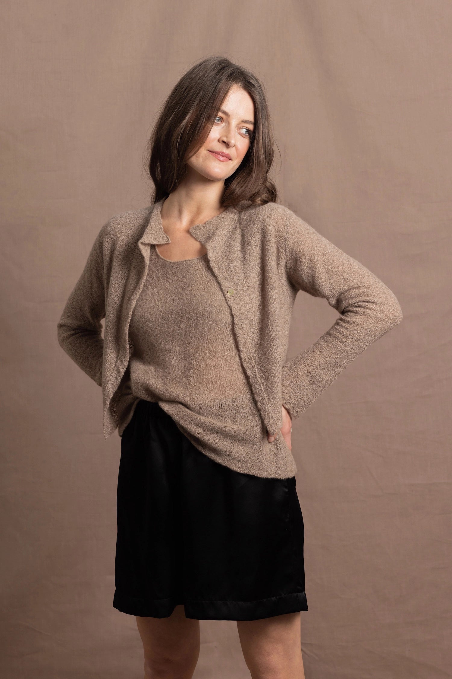 A woman wears a pure cashmere twinset cardigan with matching vest top in Beige with silk shorts in black