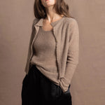 A woman wears a pure cashmere twinset cardigan with matching vest top in Beige with silk shorts in black