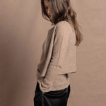 A woman wears a pure cashmere twinset cardigan with matching vest top in Beige with silk shorts in black