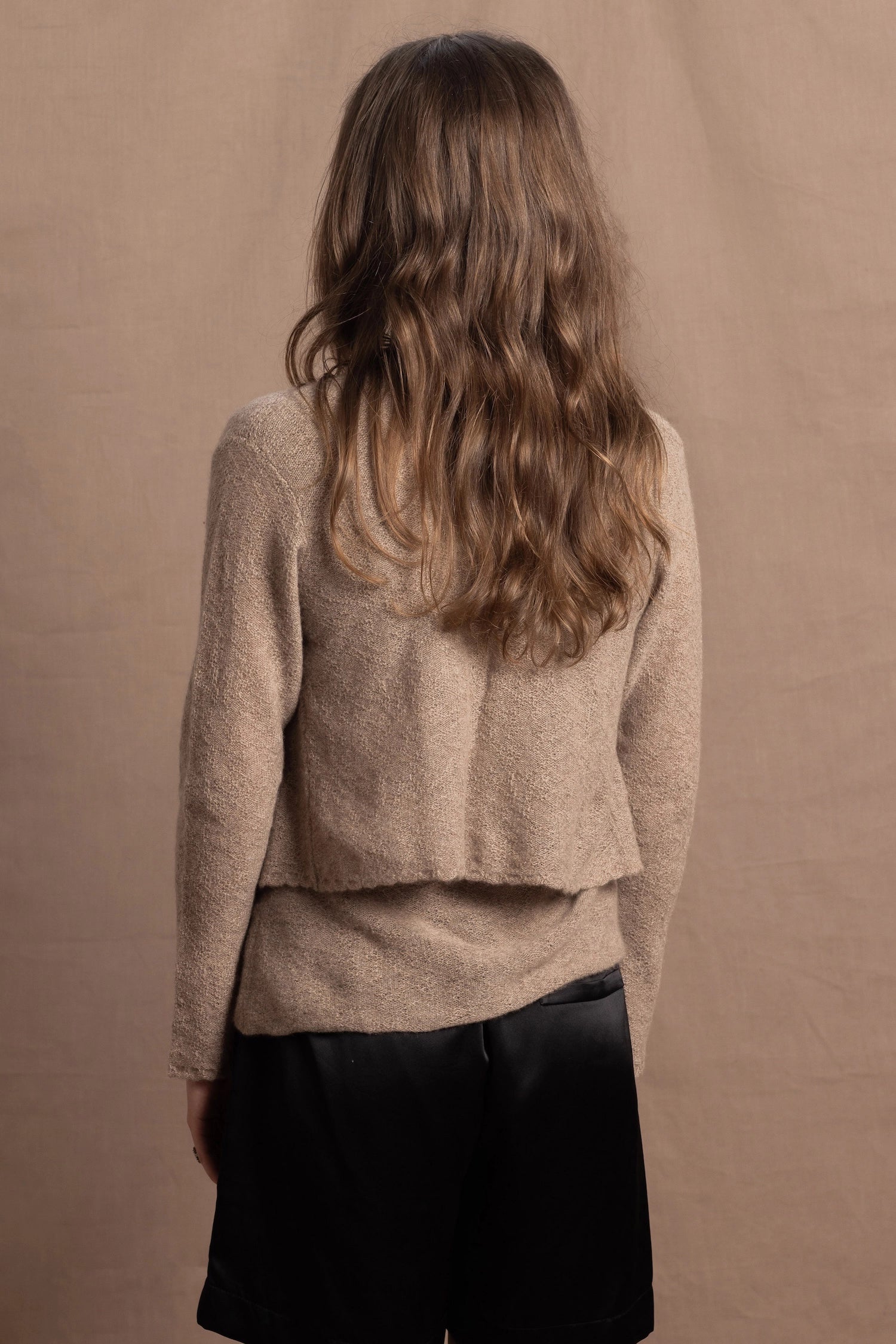 A woman wears a pure cashmere twinset cardigan with matching vest top in Beige with silk shorts in black