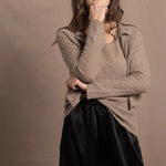 A woman wears a pure cashmere twinset cardigan with matching vest top in Beige with silk shorts in black