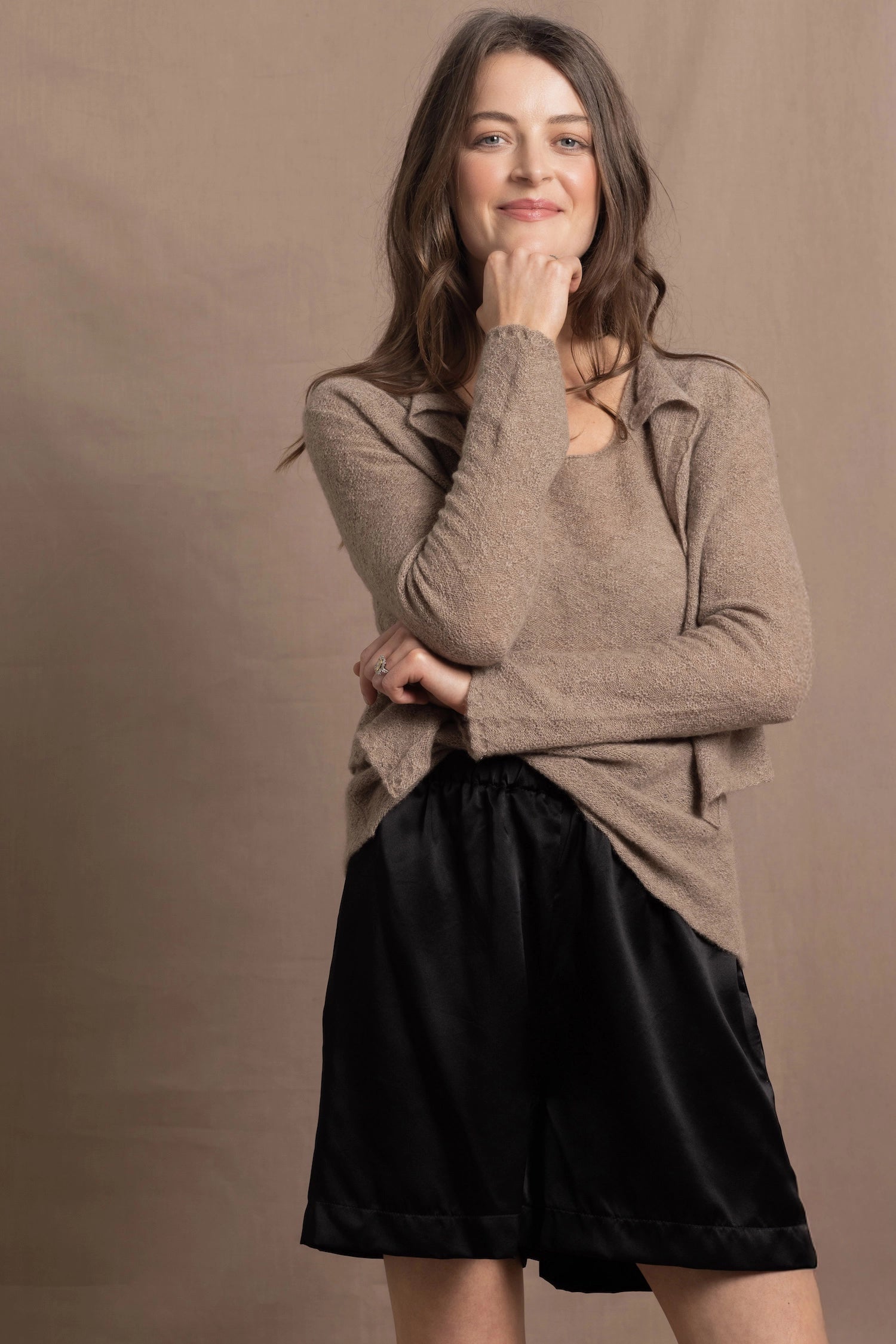 A woman wears a pure cashmere twinset cardigan with matching vest top in Beige with silk shorts in black