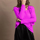 A woman wears a cashmere vest top and matching cardigan in neon pink with black silk shorts