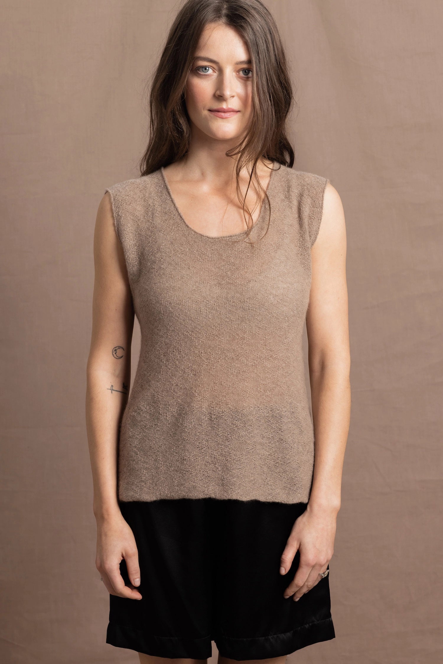A woman wears a 100% pure cashmere sleeveless vest top in beige