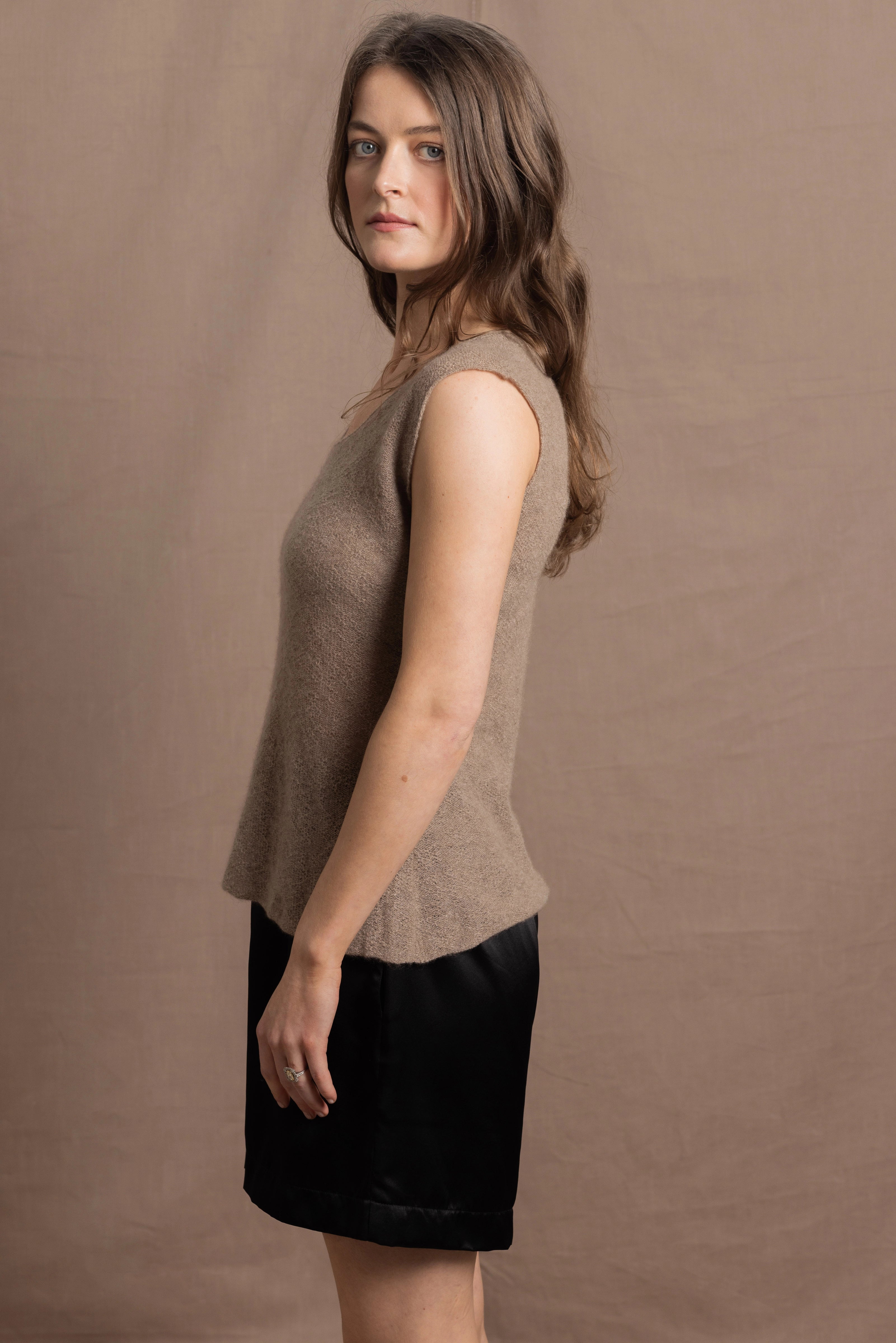 A woman wears a 100% pure cashmere sleeveless vest top in beige
