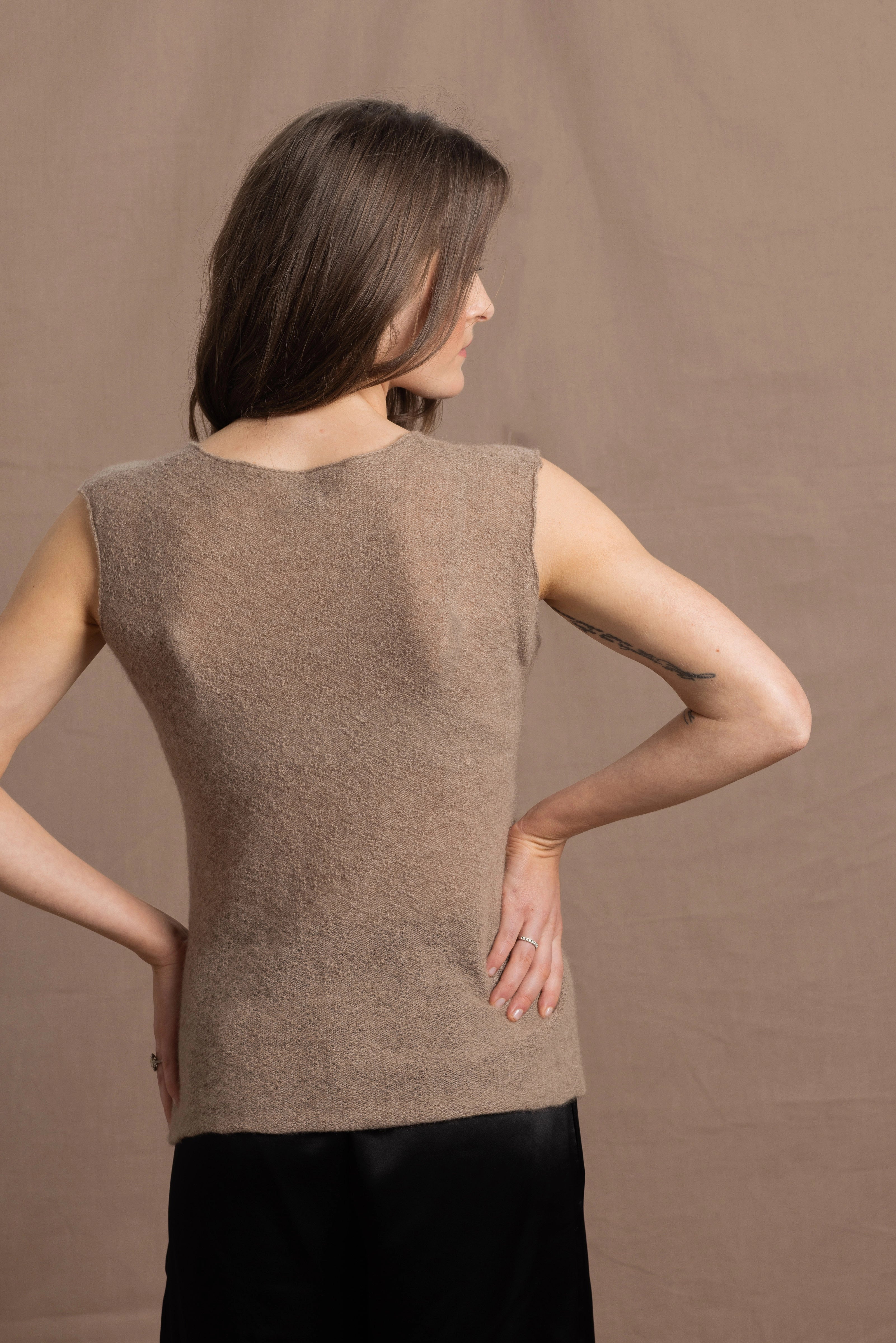 A woman wears a 100% pure cashmere sleeveless vest top in beige