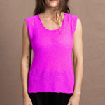 A woman wears a cashmere vest top in neon pink with black silk shorts