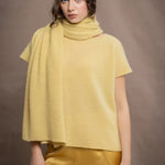 A woman wears a large cashmere scarf in pale yellow with matching cashmere beanie hat and cashmere tee sweater by Madigan Cashmere 