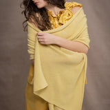 A woman wears a pointelle cashmere wrap shawl in pale yellow by Madigan Cashmere 