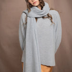 a woman wears a cashmere wrap shawl over a matching cashmere sweater and cashmere beanie in a pale blue turquoise colour