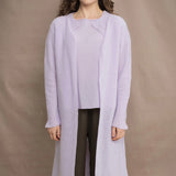 Woman wears a light purple cashmere cardigan coat over a matching cashmere tee sweater by Irish brand Madigan