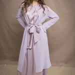 Woman wears a light purple cashmere cardigan coat over a matching silk dress by Irish brand Madigan