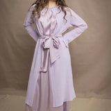 Woman wears a light purple cashmere cardigan coat over a matching silk dress by Irish brand Madigan