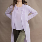 a woman wears  a 100% pure cashmere tee sweater and long cardigan coat in light purple by Irish brand Madigan Cashmere and silk trousers in dark green