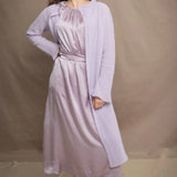 Woman wears a light purple cashmere cardigan coat over a matching silk dress by Irish brand Madigan