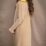 a woman wears a long cashmere cardigan coat in sand beige colour by Irish brand Madigan