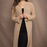 a woman wears a long cashmere cardigan coat in sand beige colour over black linen clothing by Irish brand Madigan