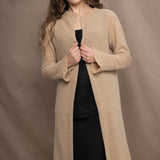 a woman wears a long cashmere cardigan coat in sand beige colour over black linen clothing by Irish brand Madigan