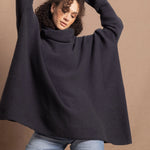 A woman wears an oversized cashmere sweater in a grey blue colour with jeans